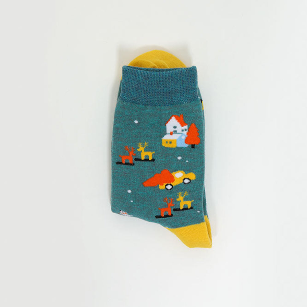 A single teal sock with a whimsical winter scene print, featuring a house, reindeer, and a red car, with yellow accents at the top and bottom, displayed on a clean white background.
