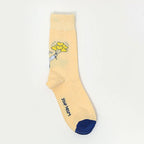 A single pale yellow crew sock with a small cartoon flower graphic near the cuff and a dark blue toe cap, shown on a plain white background.