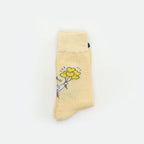 A single pale yellow sock with a small cartoon illustration of a white cat holding yellow balloons, shown on a plain white background.