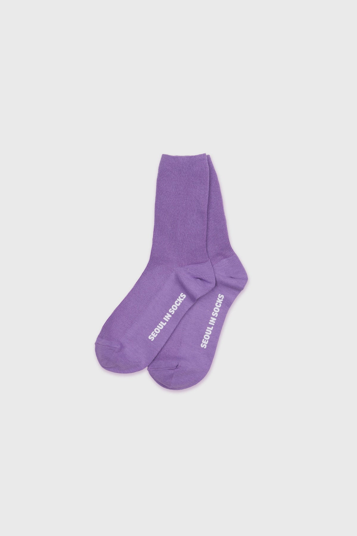 A pair of purple crew socks with white text reading 'DESIGN IN MOOSE' printed on the soles, displayed on a light gray background.