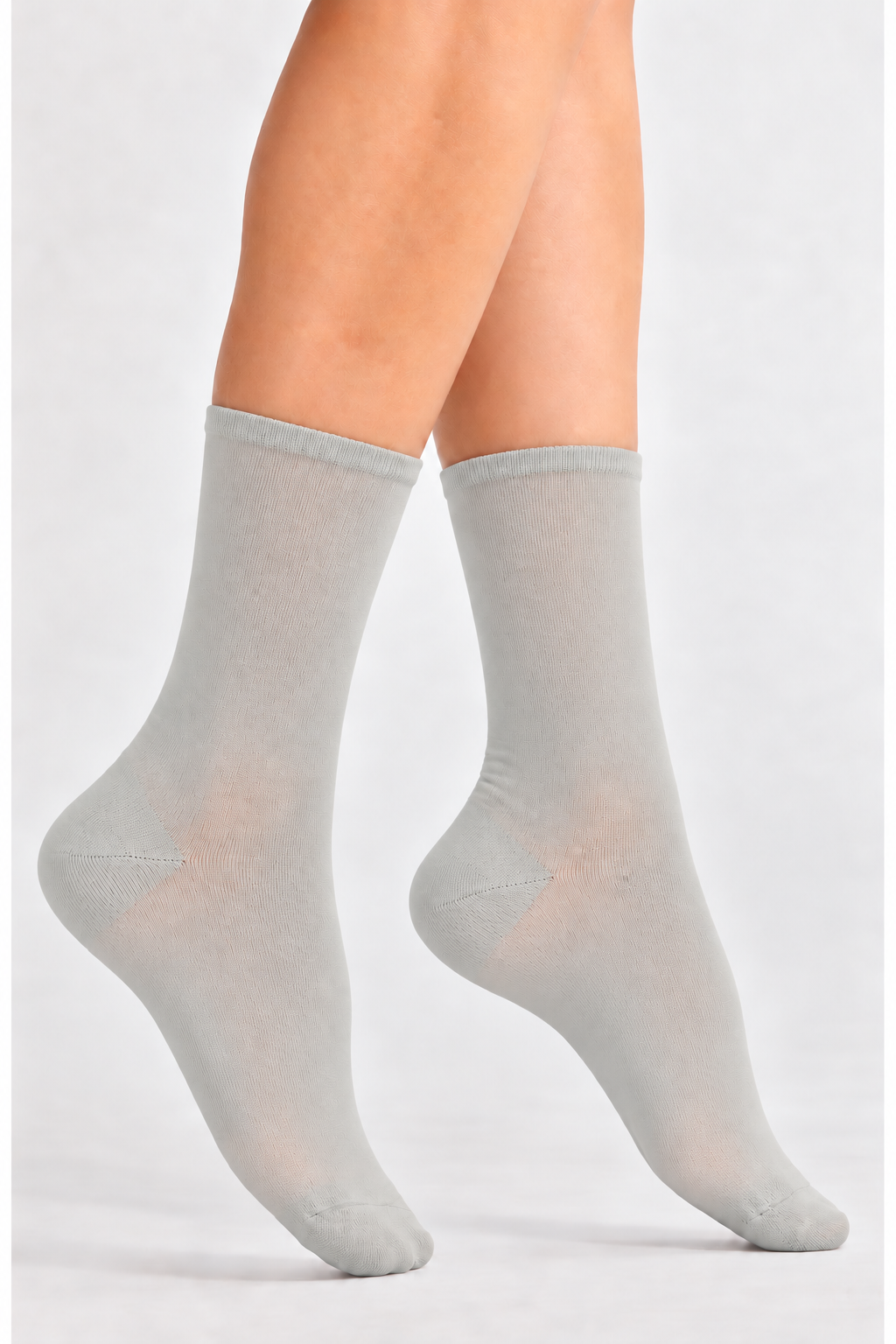 A pair of light gray crew socks worn on a person's feet, shown against a plain light gray studio background.