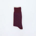 A single dark burgundy knit sock with a subtle blue diamond pattern, laid flat on a clean white background.
