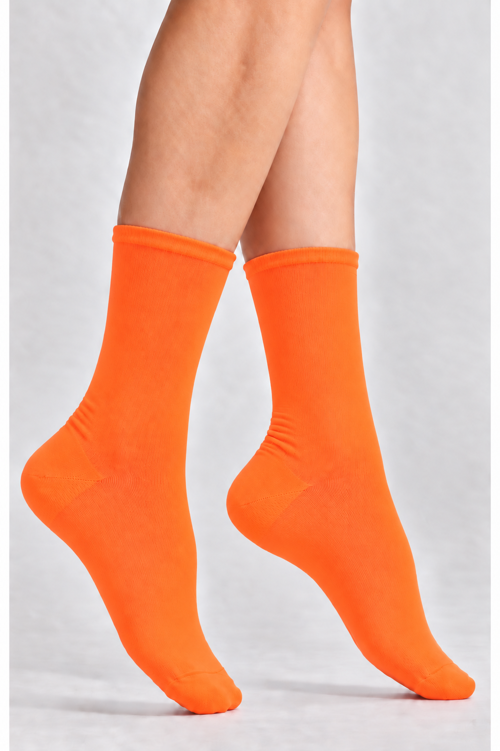 Bright neon orange crew socks worn on a person's feet, shown against a light gray studio background.