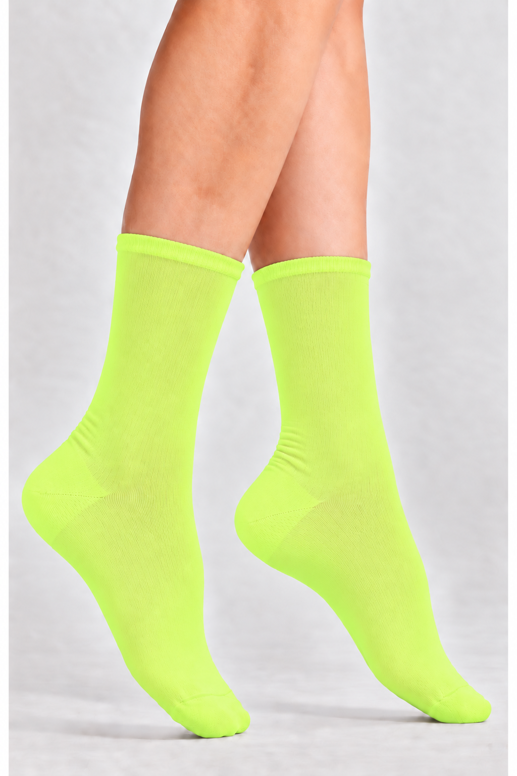 A pair of bright neon yellow-green crew socks worn on a model's feet, shown against a light gray studio background.