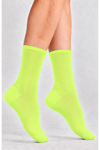 A pair of bright neon yellow-green crew socks worn on a model's feet, shown against a light gray studio background.