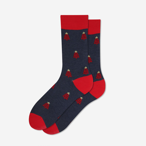A pair of crew socks with a dark navy blue body, featuring a repeating pattern of small red Christmas trees with gold stars, accented with solid red heels, toes, and cuffs, displayed on a light gray background.