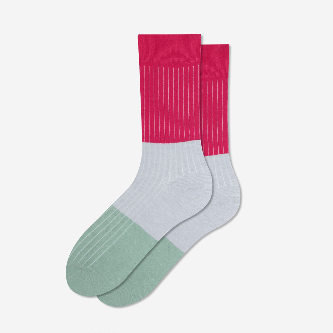 A pair of crew socks with a color-blocked design featuring a vibrant pink upper calf section with thin white vertical stripes, a light gray midfoot section, and a sage green toe section with subtle horizontal stripes, set against a clean off-white background.