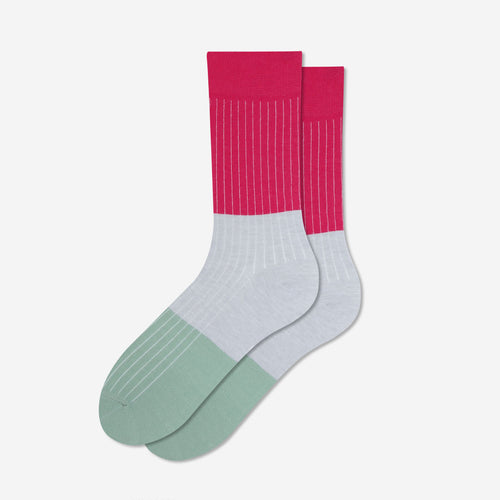 A pair of crew socks with a color-blocked design featuring a vibrant pink upper calf section with thin white vertical stripes, a light gray midfoot section, and a sage green toe section with subtle horizontal stripes, set against a clean off-white background.