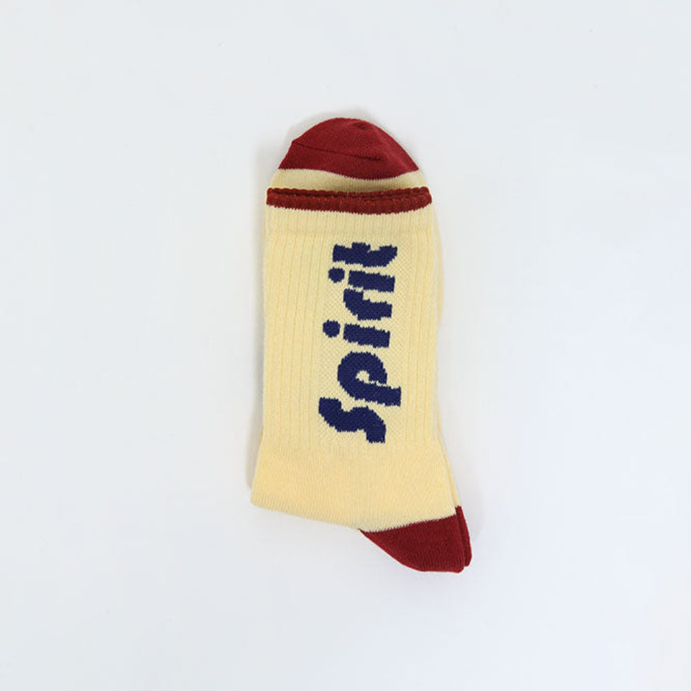 A single ribbed ankle sock in pale yellow with a dark red toe and heel, and the word 'Spirit' printed vertically in dark blue. The sock is photographed flat against a plain white background.