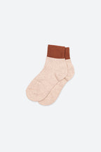 A pair of ankle socks in a light heathered peach-beige color with a contrasting ribbed brown cuff, displayed against a clean white background.